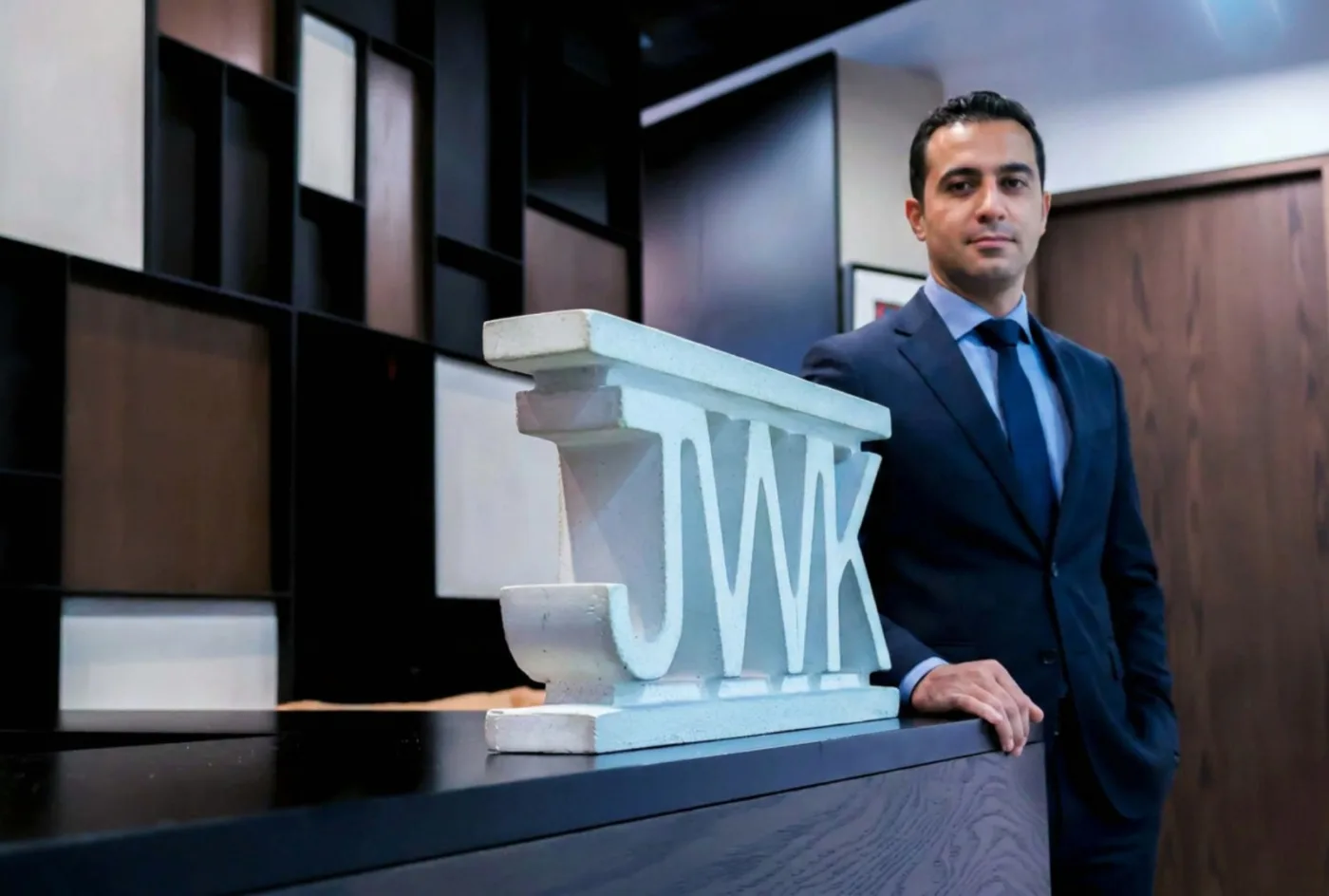Socio de J.W.K. Business en la recepción del despacho, junto al logotipo escultórico